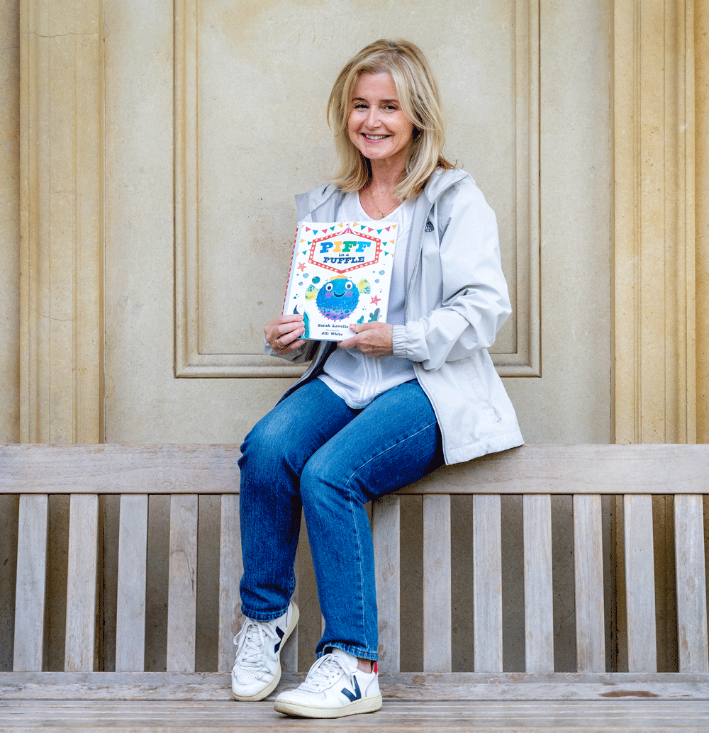 a portrait of the author Sarah Lavelle, sitting on a bench and holding a copy of her book Piff in a Puffle